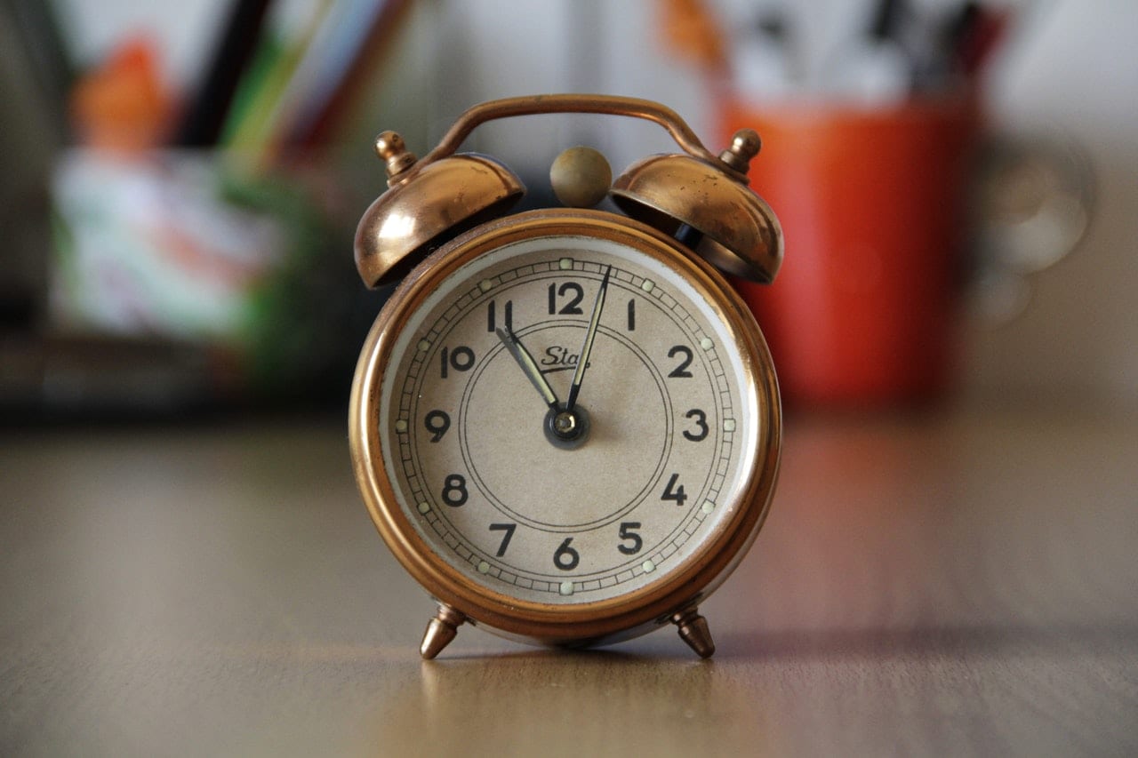 old-fashioned alarm clock sitting on desk.