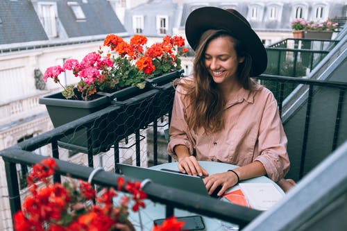 Business professional sitting outside working on laptop next to spring flowers