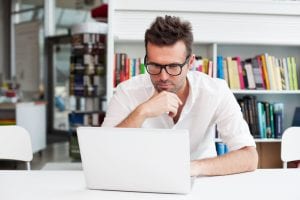 A person looking at a computer screen reading the best appointment scheduling software reviews.